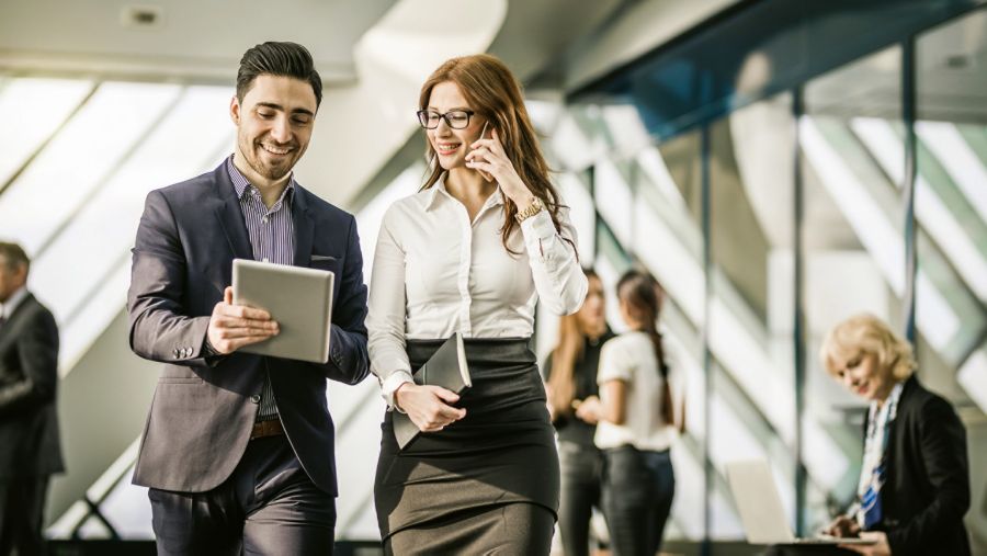 man and woman walking through hallway looking at tablet