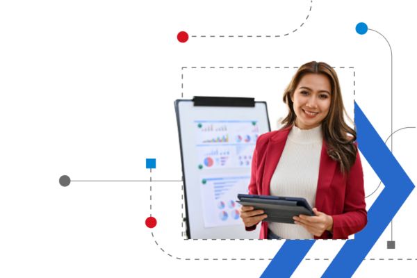 A woman holds a laptop in front of a board with charts