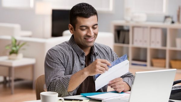 A man looking at a piece of paper he opened from an envelope