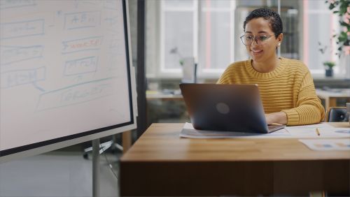 A woman sitting while typing on her laptop.