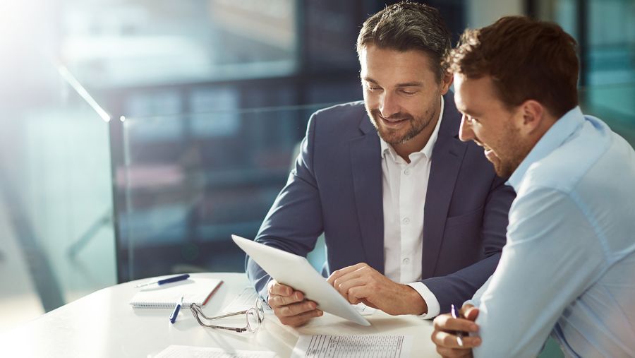 A businessman helping someone on a laptop