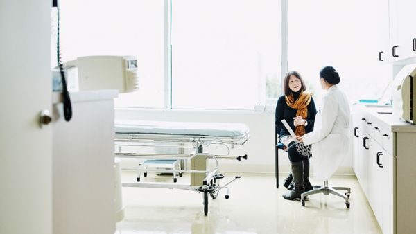 A female doctor talking to a female patient in an examination room.