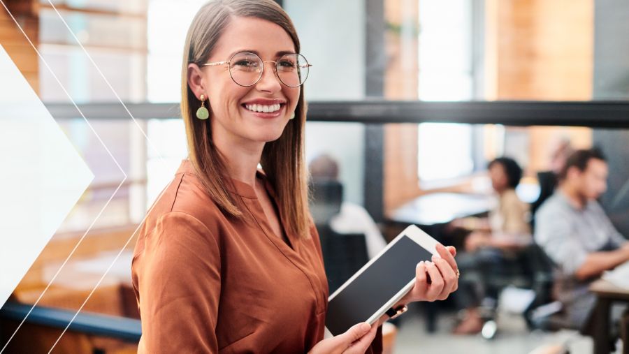 A woman in an office smiling holding a tablet