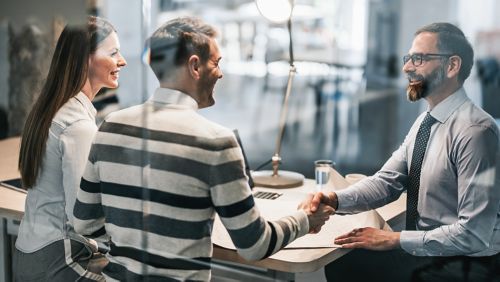 Banker shakes hands with young couple