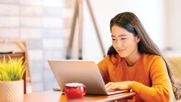 A woman smiling and working on a laptop.