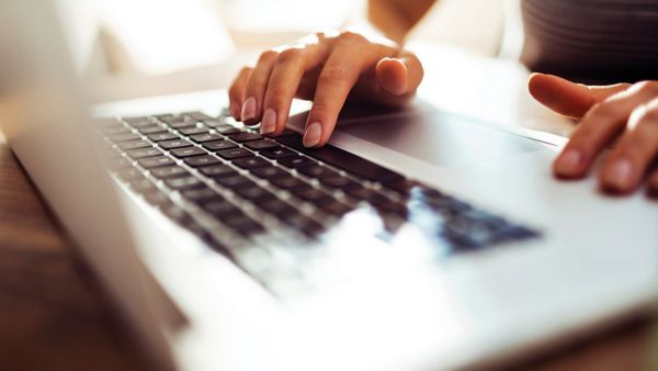 A person's hands typing on a laptop.
