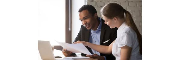 Male and female professional services coworkers analyze data on printed paper