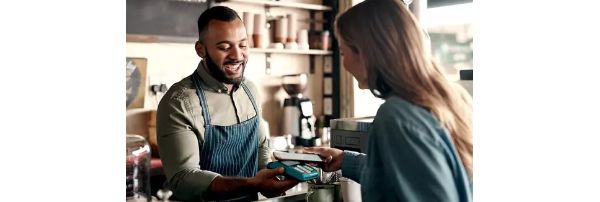 A restaurant worker presents a contactless terminal for a customer to make a payment