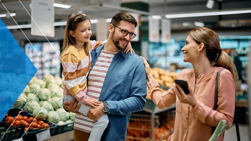Young couple with child shopping in a grocery store while mom looks on her phone.