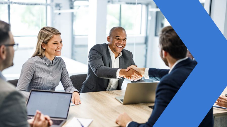 business associates shake hands while seated at a table 