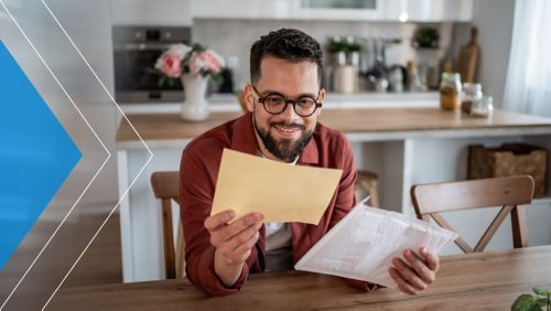 Man reading mail in his kitchen.