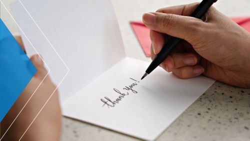 Business owner signing a "thank you" card.