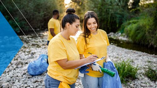 Two volunteers working on cleaning a river of trash.