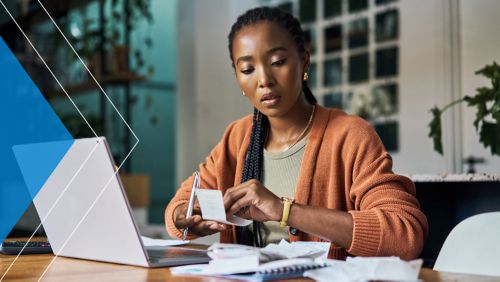 Woman looking over receipts at her computer. 