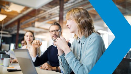 Group of coworkers meeting in office space with laptops.