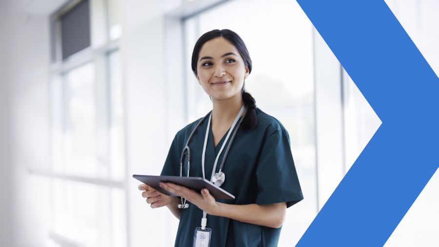Female medical provider smiling and holding tablet in medical office.