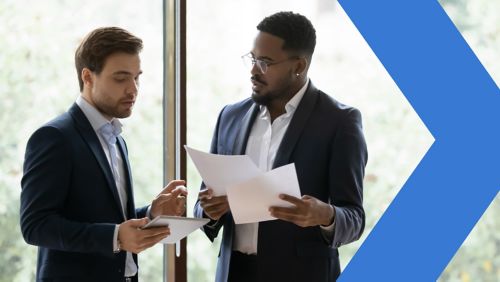 Two diverse  businessmen holding papers and looking at tablet