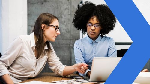 Female employee smiling and talking in front of laptop in office.