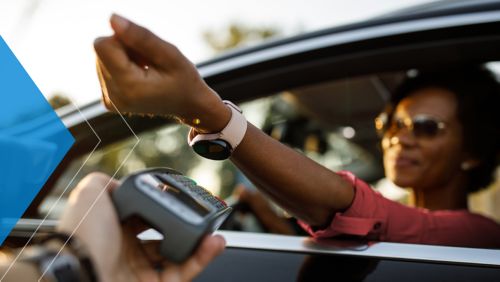 Woman using her smartwatch to pay at a drive through.
