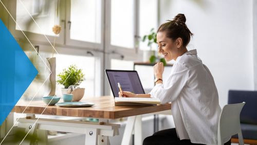 Young woman smiling and working in her at-home office space.