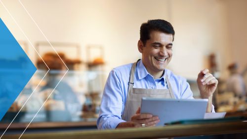 Merchant smiling at his tablet after receiving a cash advance through his software provider.
