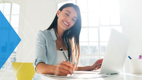 Woman smiling at desk paying bills online. 