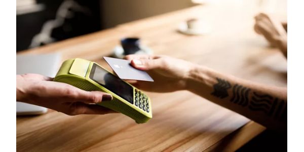 A person using tap to pay with a credit card at a business.