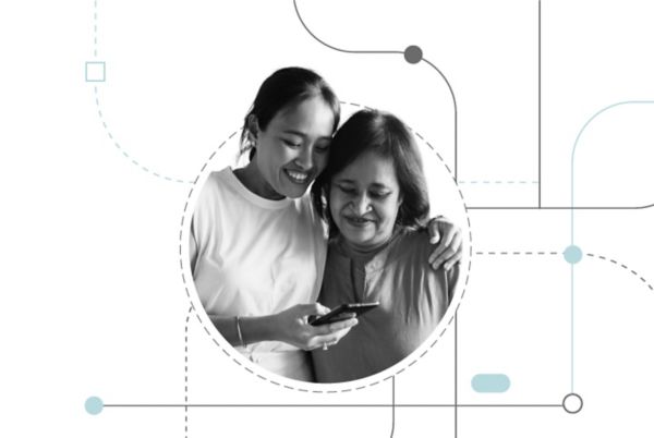 Two women standing together looking at a mobile phone and smiling