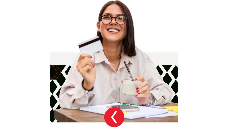 A woman sits at a table holding a credit card