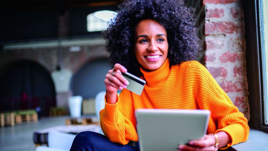 A woman at a table holding a credit card in her hand and smiling