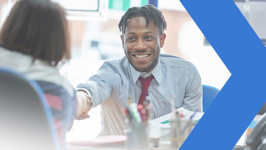 Smiling banker shakes hand with small business owner in office.