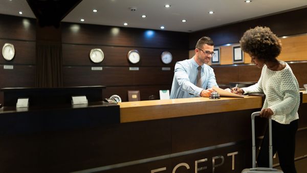 A woman smiling while talking to the male concierge at a hotel.
