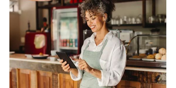 A woman standing in a restaurant holding a small tablet. 