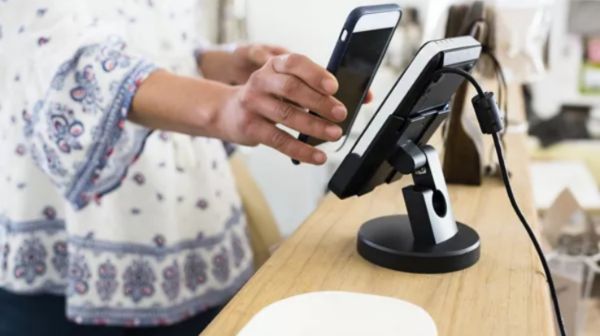 A person using their phone for tap-to-pay to purchase items at a retail shop.