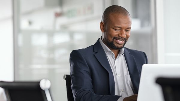 A man working on his laptop smiling.