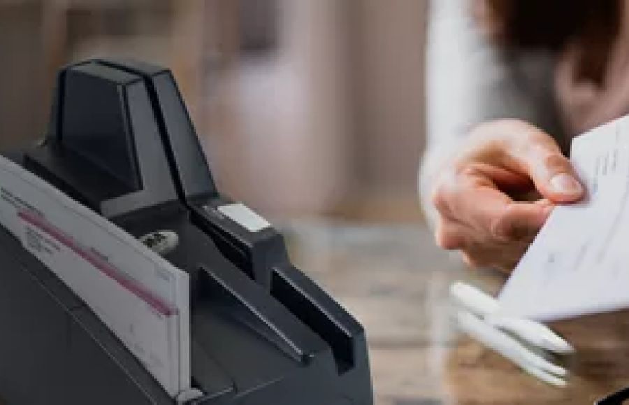 A customer hands a bank teller multiple checks at a bank branch.