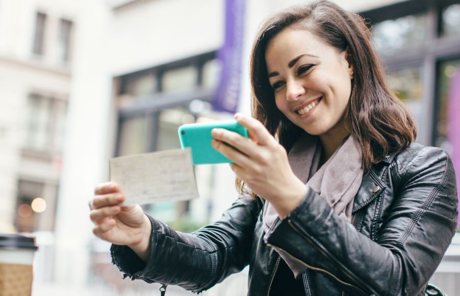A woman takes a photo of a check with her mobile phone