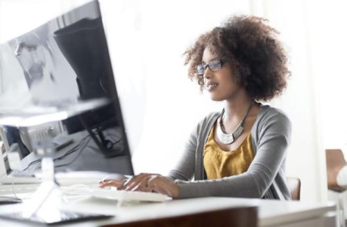 A woman working at her desktop computer typing.