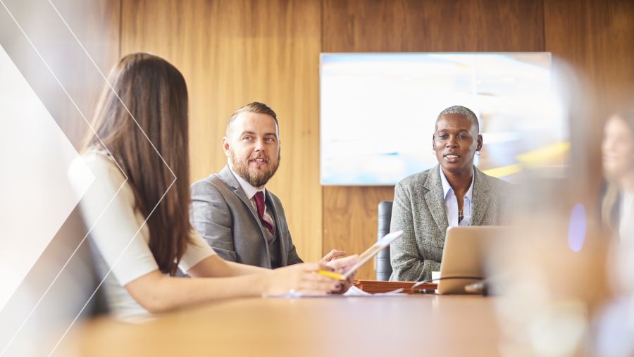 A group of coworkers at a meeting table discussing payment fraud