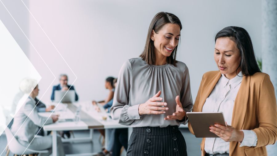 Two women in an office holding a tablet discussing AR automation