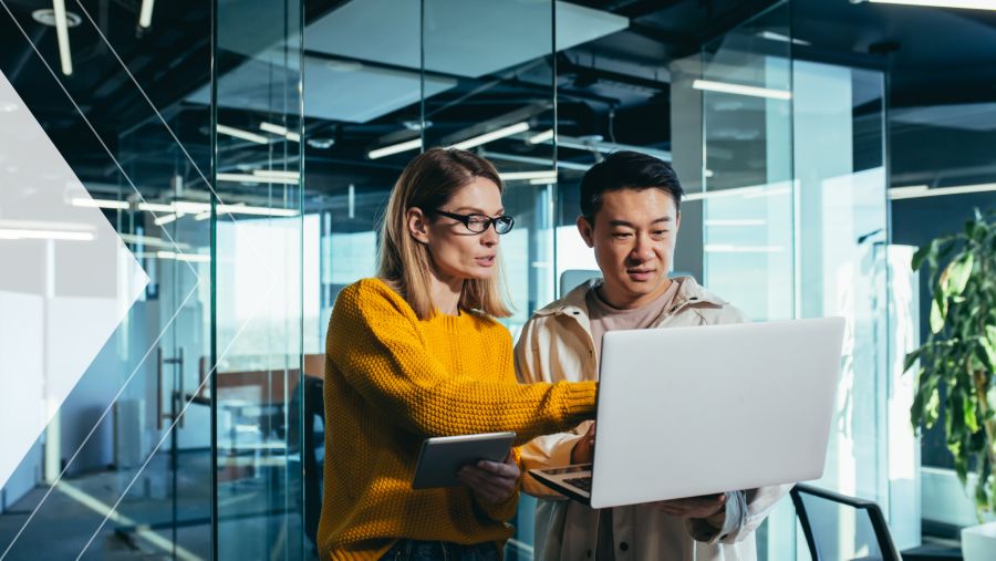 A businesswoman conversing with coworker while on a laptop