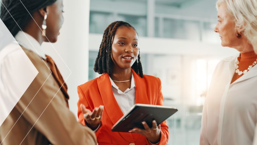 A businesswoman conversing with coworker while on a tablet