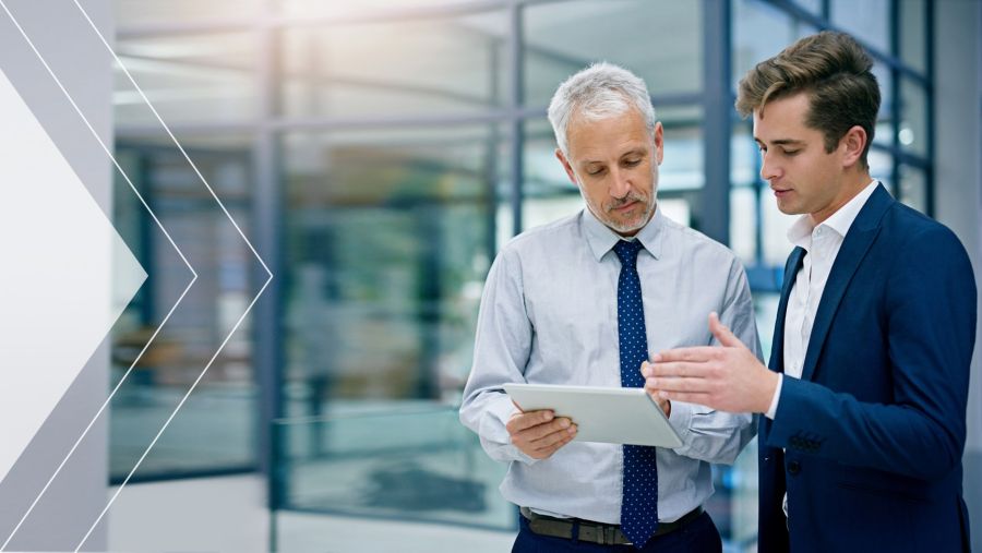 Two coworkers having a conversation while looking at a tablet